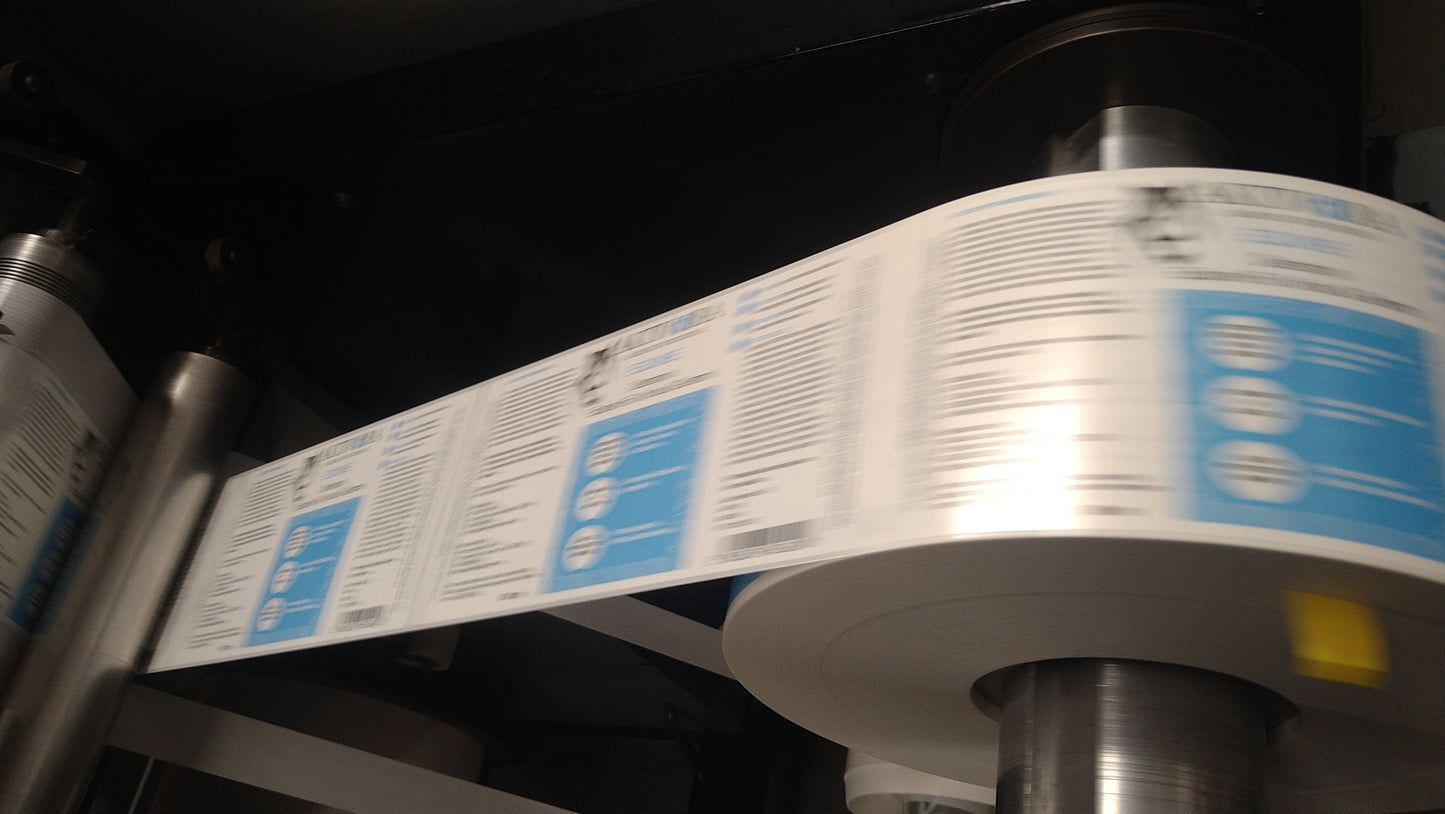 Roll of labels with text and blue stickers on a machine.