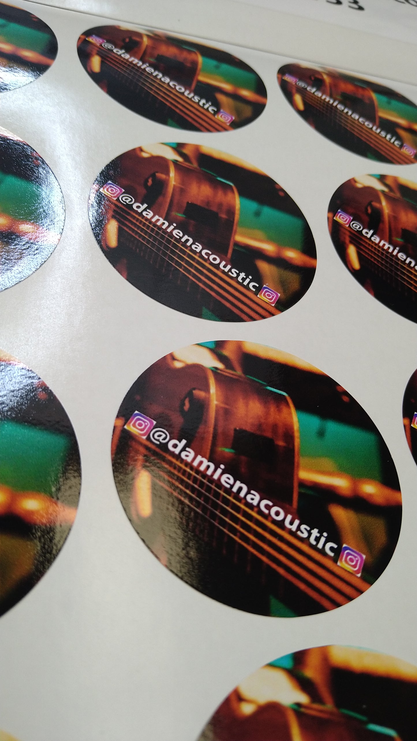 Sheet of round stickers with acoustic guitar design and 'damienacoustic' branding.