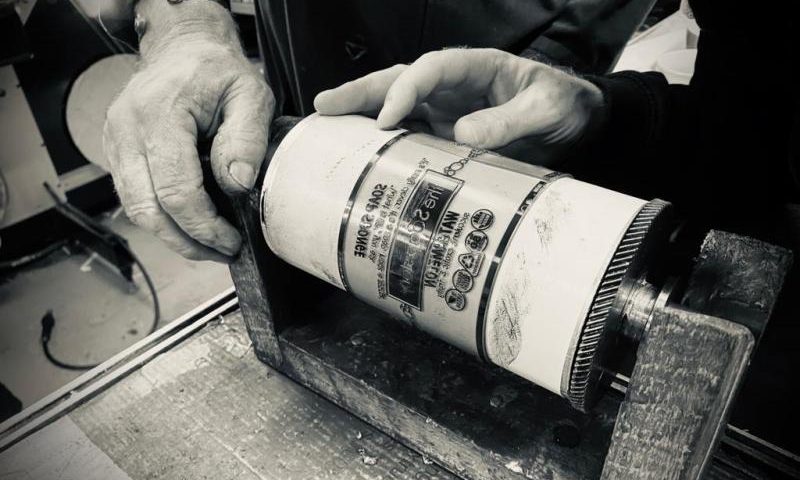 An image of father and sons hands working on a printing plate